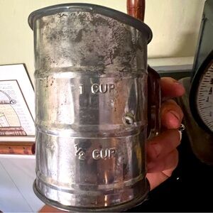 Antique, aluminum sifter with wooden handle.
